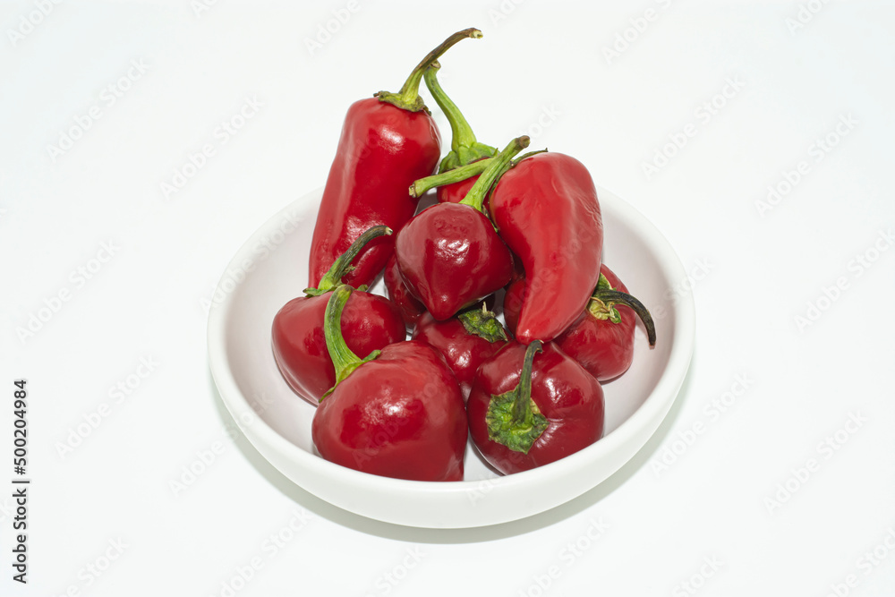 red peppers on a plate.Bright red ripe peppers in a white bowl, counter in the kitchen. red peppers on a plate.Bright red ripe peppers in a white bowl, counter in the kitchen.