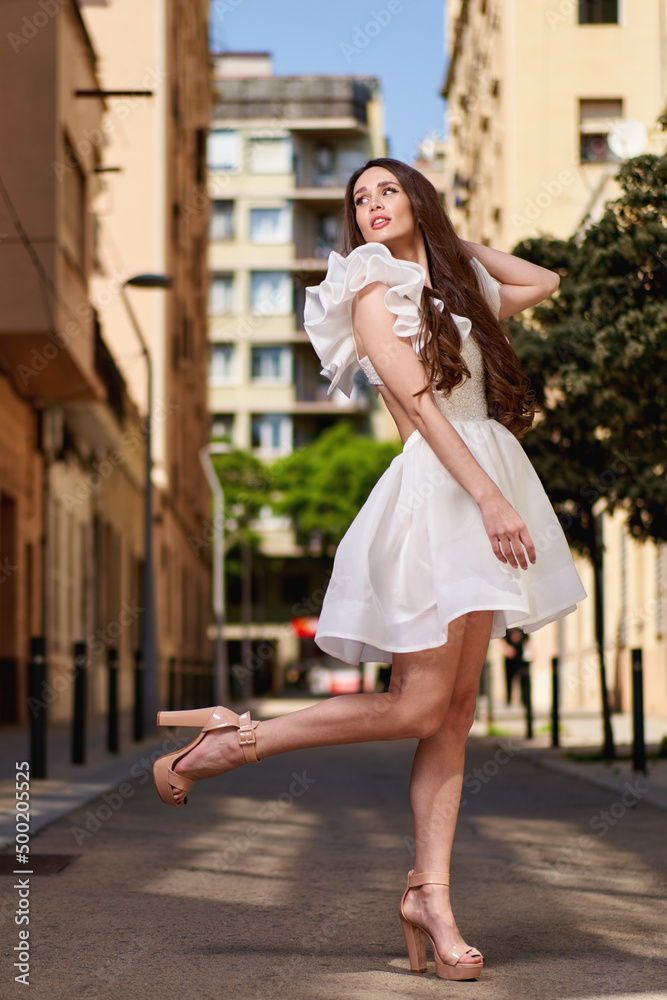 Young beautiful girl posing outdoor, wearing fashionable white dress. Summer style.