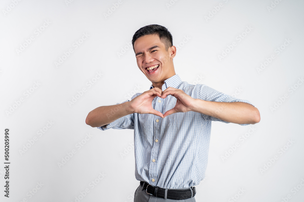 young businessman forming a heart with finger gestures on isolated background young businessman forming a heart with finger gestures on isolated background