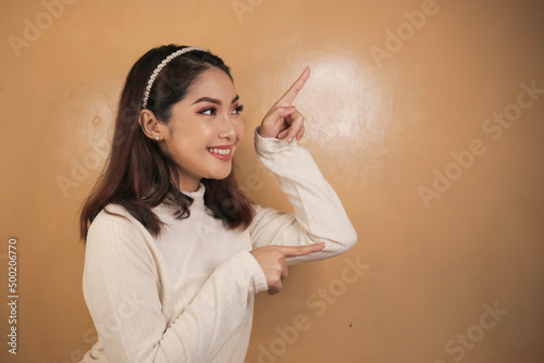 Happy and smile face with smile of young Asian girl with hand point on empty space.