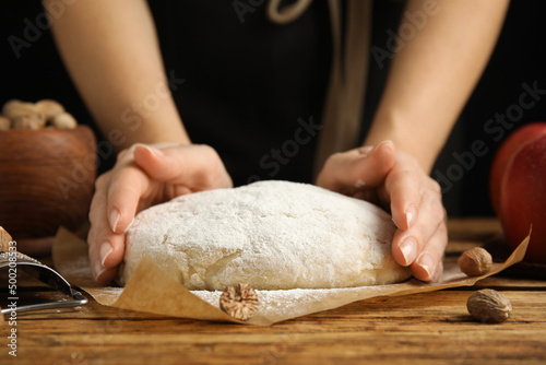 Woman with raw dough at wooden table, closeup