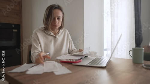 Young woman getting stressed over finances. Young woman looking worried over bills in kitchen. Working from home in quarantine lockdown. Social distancing Self Isolation