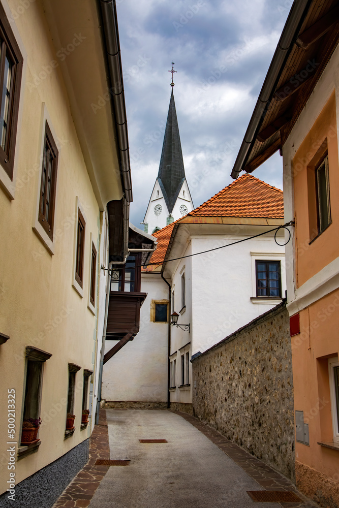Narrow street with old houses and tower of church in alpine town Radovljica, Slovenia