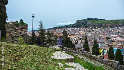 Time lapse shot showing person sitting on rock and watching cityscape of Corleone on Sicily photo