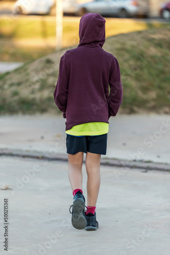 Rear view of a young hooded boy walking away