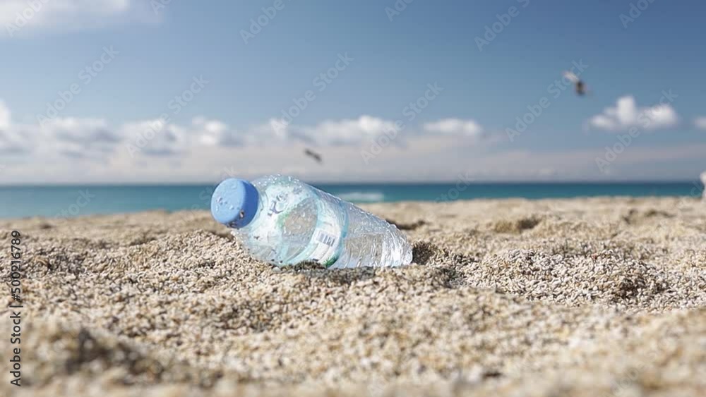 Garbage pollution of the planet. Empty plastic bottle on the beach sand. Consequences of human life