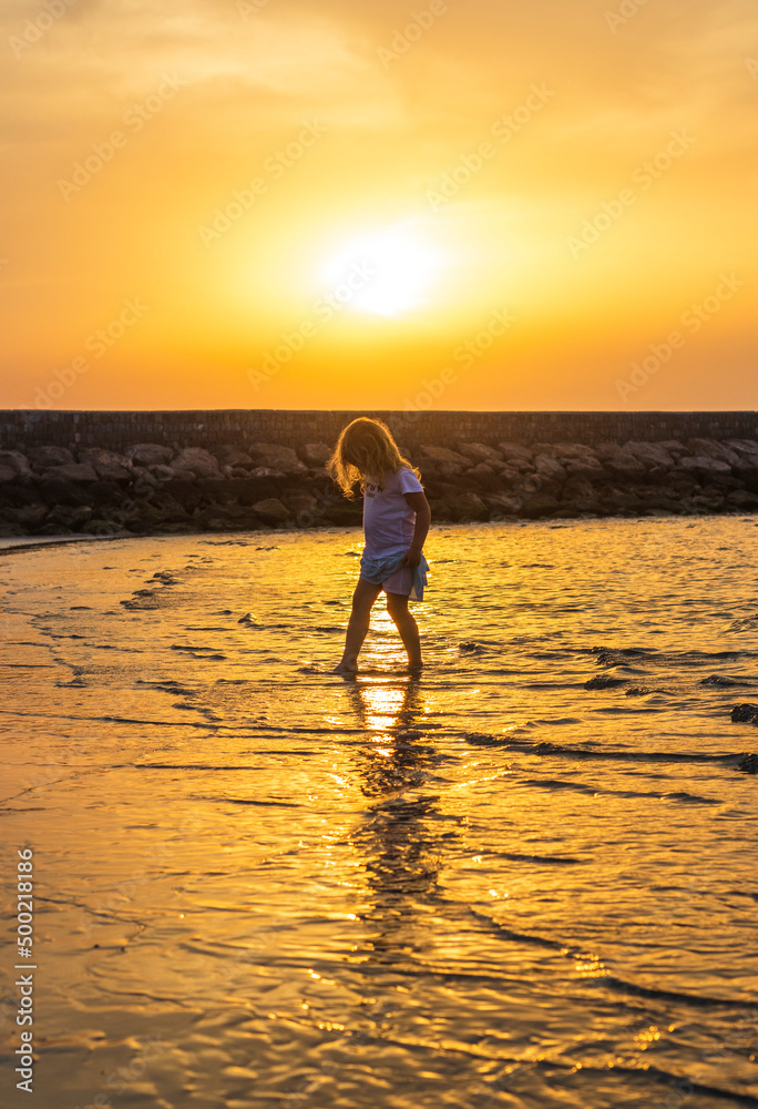 Shot of a little girl playing on the beach during sunset hour. Outdoors