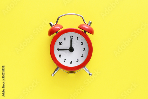 Red alarm clock on a yellow background
