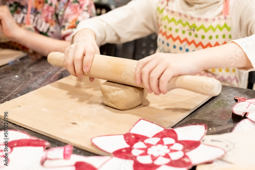 child potter rolls a brown clay with rolling pin on a special board on a wooden table to make a plate.Pottery workshop.Pottery workshop. teaching schoolchildren. hobbies and leisure for children.