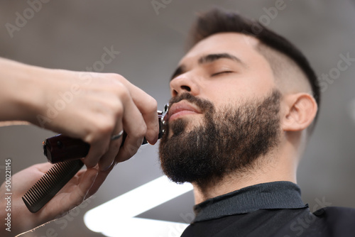 Professional hairdresser working with client in barbershop, low angle view