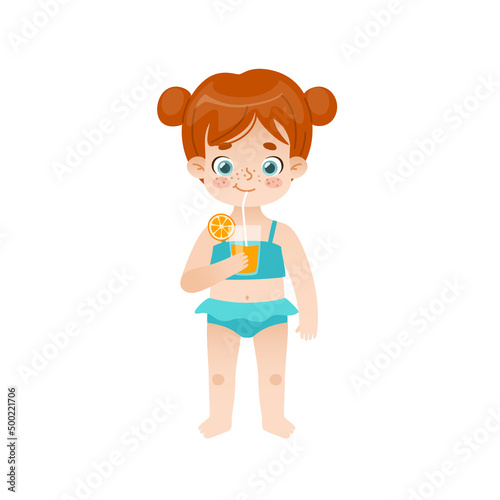 Cute baby girl standing and drinking orange juice. Adorable child with red hair and freckles on summer vacations.