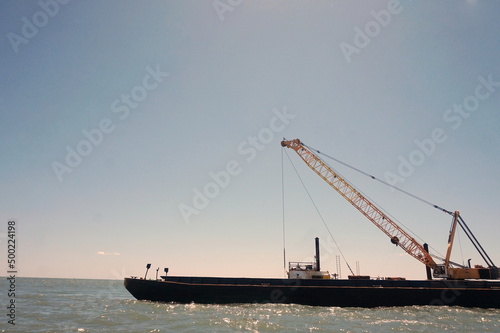 Crane on a Barge in Ocean Water wtih Blue Sky