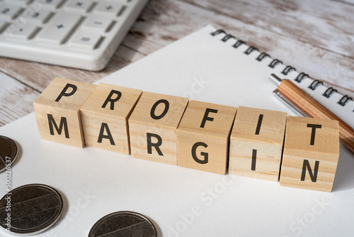 売上高利益率のイメージ｜「PROFIT MARGIN」と書かれた積み木、電卓、コイン、ノート、ペン