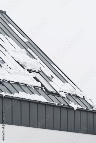 Detal architektoniczny na budynek, dom jednorodzinny. Dach wykonany z blachy aluminiowej w kolorze szarym. Okno dachowe