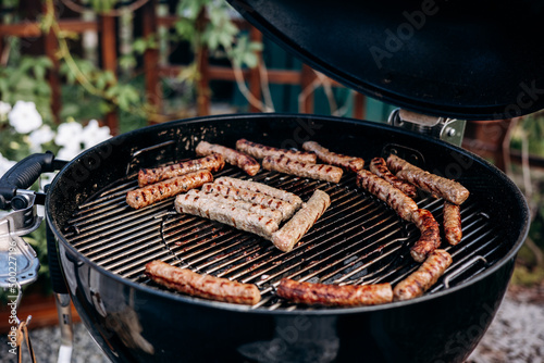 Backyard BBQ. Close-up of grilling sausages of meat on barbecue. Man preparing tasty sausages