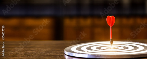 Red dart arrow hitting in the target center of dartboard on bullseye with sun light vintage style, Target marketing and business success concept photo