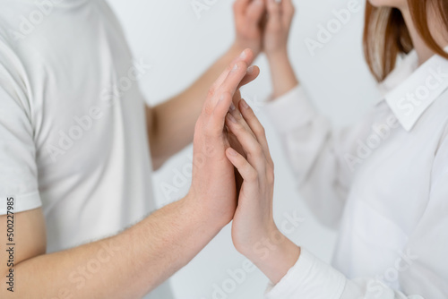 Cropped view of blurred couple touching hands isolated on white.