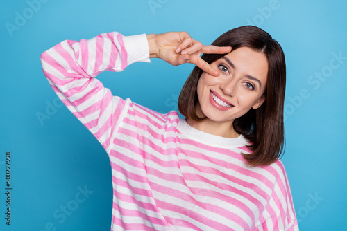 Photo of cute millennial bob hairdo lady show v-sign wear striped shirt isolated on blue color background
