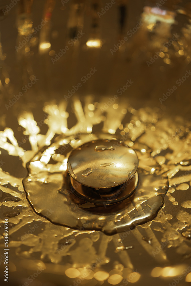 Expensive shining golden wet sink with water drops, a detail of a rich luxury interior, top view Expensive shining golden wet sink with water drops, a detail of a rich luxury interior, top view