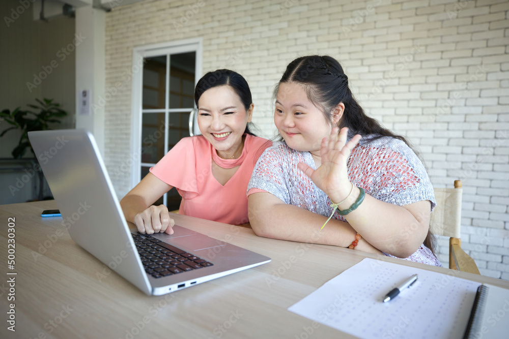 down syndrome teenage girl and her teacher studying how to use laptop computer and talking online to someone