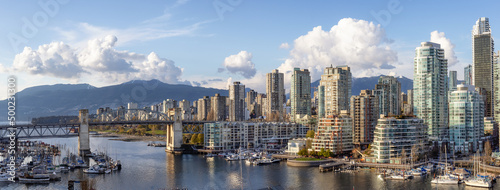 Panoramic Aerial View of Granville Island in False Creek with modern city skyline and mountains in background. Downtown Vancouver, British Columbia, Canada.