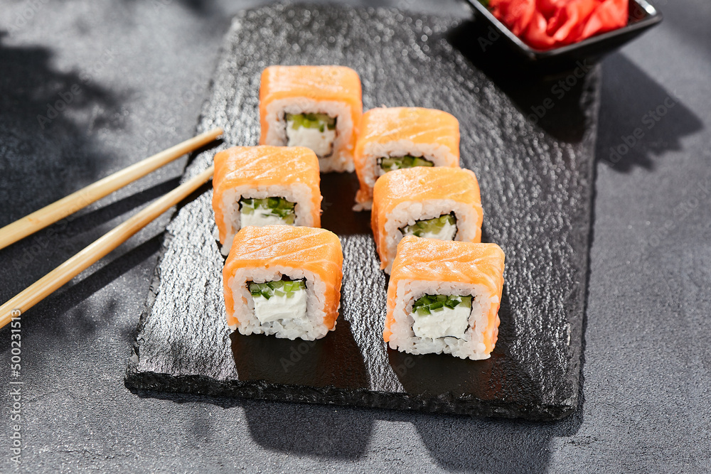 Maki sushi on dark stone table. Philadelphia maki with salmon. Sushi
