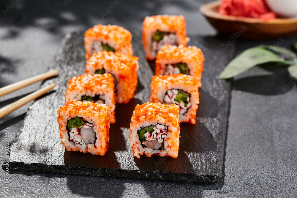 Maki sushi on dark stone table. California maki with tobiko. Sushi roll