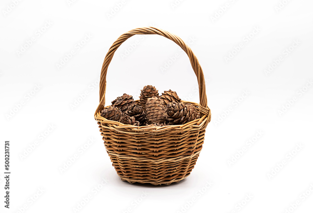 Cedar cones with pine nuts in wicker basket on a white background.