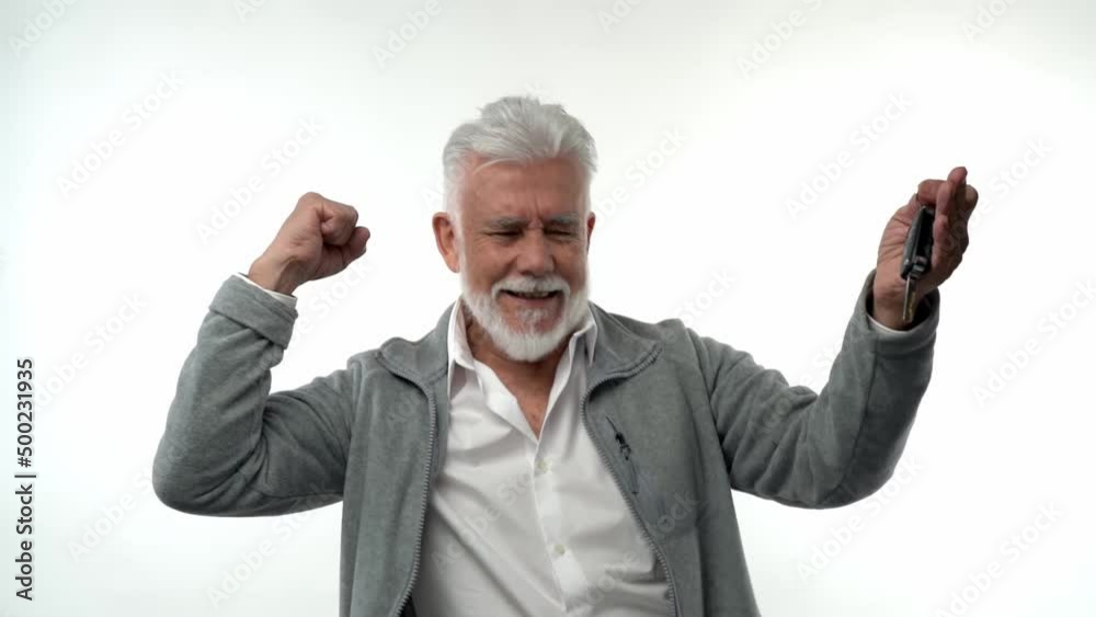 Stylish emotional old man with a gray beard shows the presence of the keys to the new purchased car. On a white isolated background. Trend character of pensioner. Stylish emotional old man with a gray beard shows the presence of the keys to the new purchased car. On a white isolated background. Trend character of pensioner.