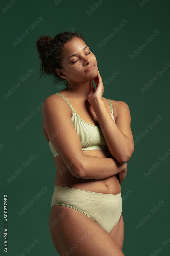 Portrait of young tender woman posing in comfortable cotton underwear isolated over green studio background. Natural beauty