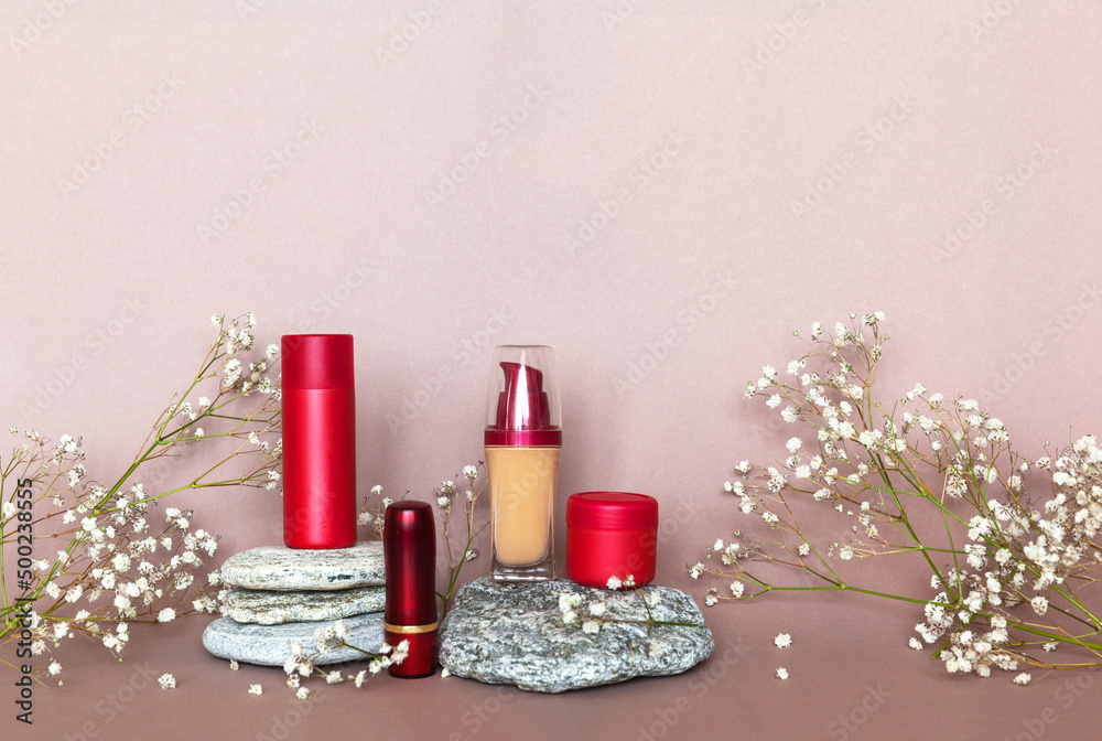 Natural cosmetic products for facial skin care on pebble stone pedestal and gypsophila flowers on beige background. Anti-aging cosmetics with hyaluronic acid. Sun protective lipstick and cream