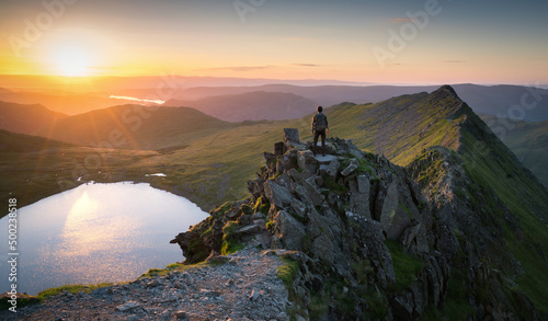 Obraz na plátně Hiker surveying the summit of Helvellyn at sunrise, with first light illuminatin