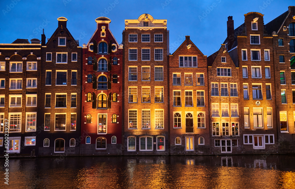 Old lighted houses bulidings at lighted sunset river channel in Amsterdam city