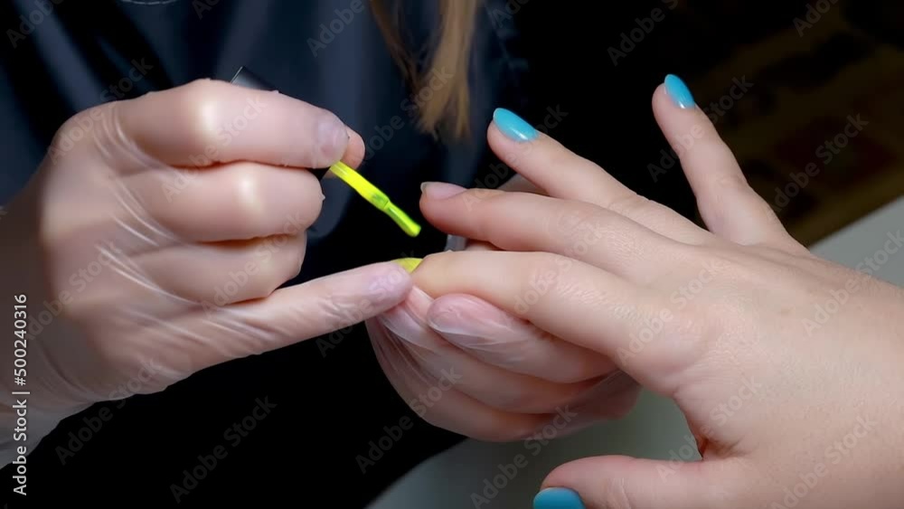 manicure in blue yellow colors the master is applied to the nail with a yellow nail polish brush manicure in blue yellow colors the master is applied to the nail with a yellow nail polish brush