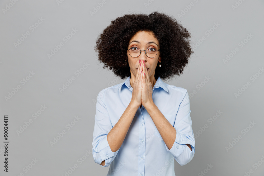 Young shocked surprised employee business corporate lawyer woman of African American ethnicity wear classic formal shirt work in office cover mouth with hand isolated on grey color background studio Young shocked surprised employee business corporate lawyer woman of African American ethnicity wear classic formal shirt work in office cover mouth with hand isolated on grey color background studio