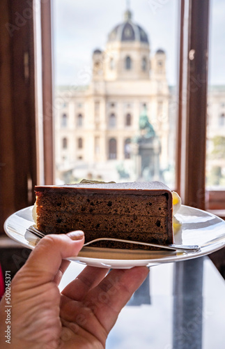 Photography Hand with piece of famous Sachertorte chocolate cake with apricot jam of Austria