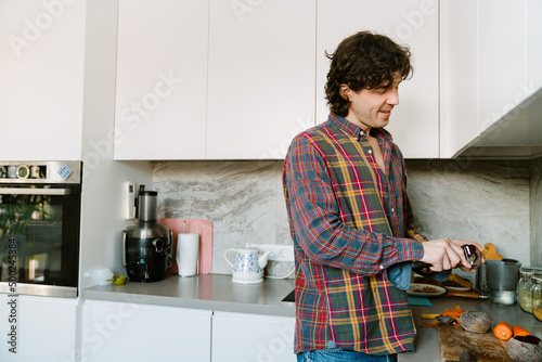 White man cutting vegetables while cooking lunch in kitchen