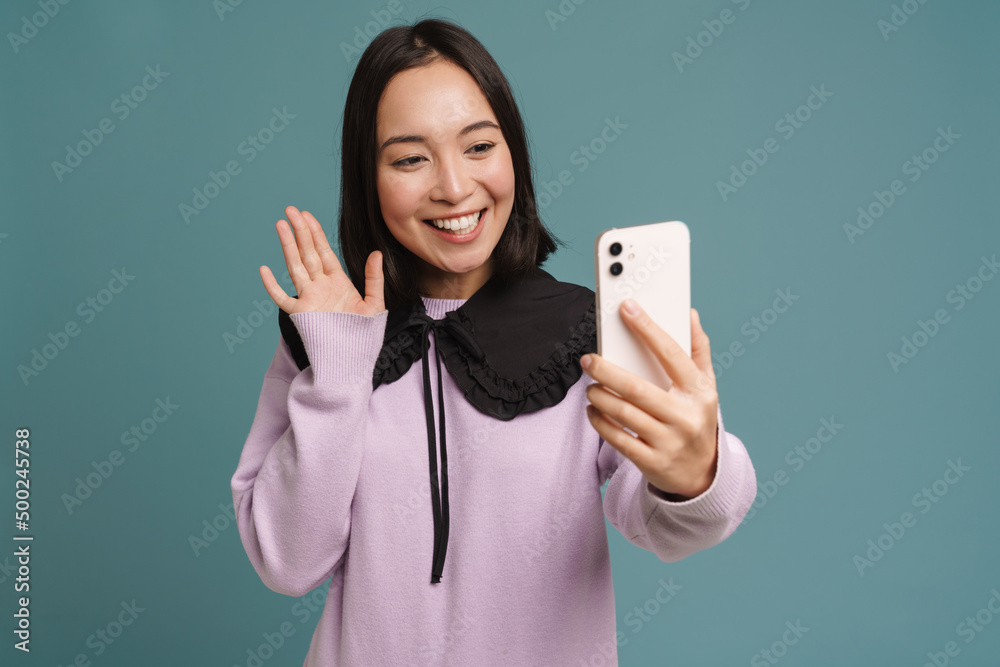 Young asian woman gesturing while taking selfie on cellphone Young asian woman gesturing while taking selfie on cellphone
