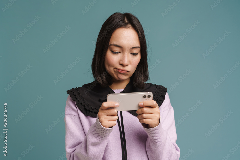 Young asian woman playing online game on mobile phone Young asian woman playing online game on mobile phone