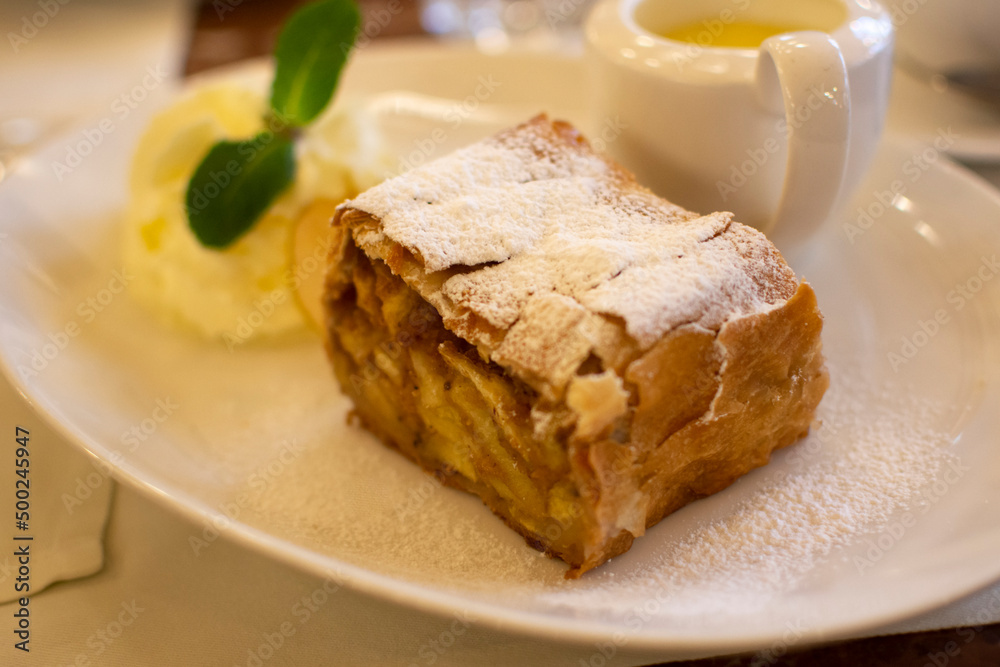 Austrian sweet dessert, portion of apple strudel with whippen cream and hot vanilla sauce served in old bakery cafe in Vienna, Austria