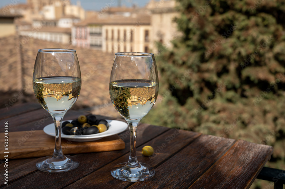 Two glasses of Spanish dry rueda white wine served with olives on roof terrace with view on old part of Andalusian town Granada, Spain Two glasses of Spanish dry rueda white wine served with olives on roof terrace with view on old part of Andalusian town Granada, Spain