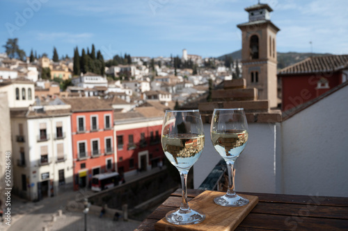 Two glasses of Spanish dry rueda white wine served on roof terrace with view on old part of Andalusian town Granada, Spain