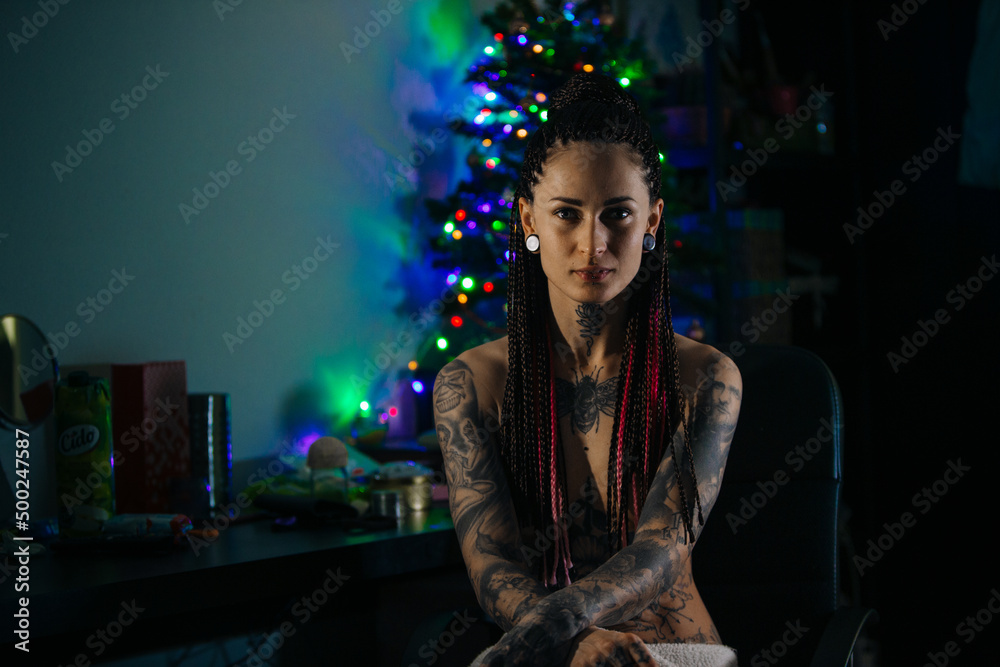 Tattooed girl is sitting in the dark room
