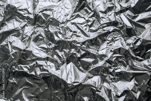 Background, texture of silver shiny foil, colored crumpled wrapping paper. Photo, top view, copy space.