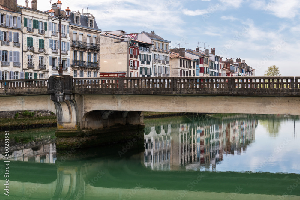 Naklejka premium Reflection of the houses on the Nive River. Marengo Bridge. Baiona. French Basque Country