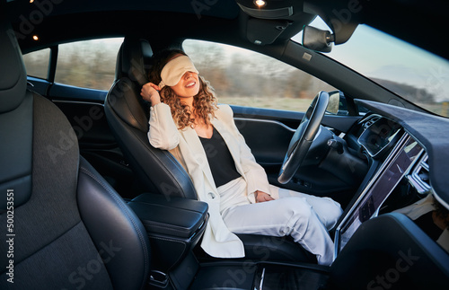 Business woman resting on driver\'s seat in automobile with bandage for sleep while her car moving on full autopilot. Modern opportunity to rest while vehicle driving independently.