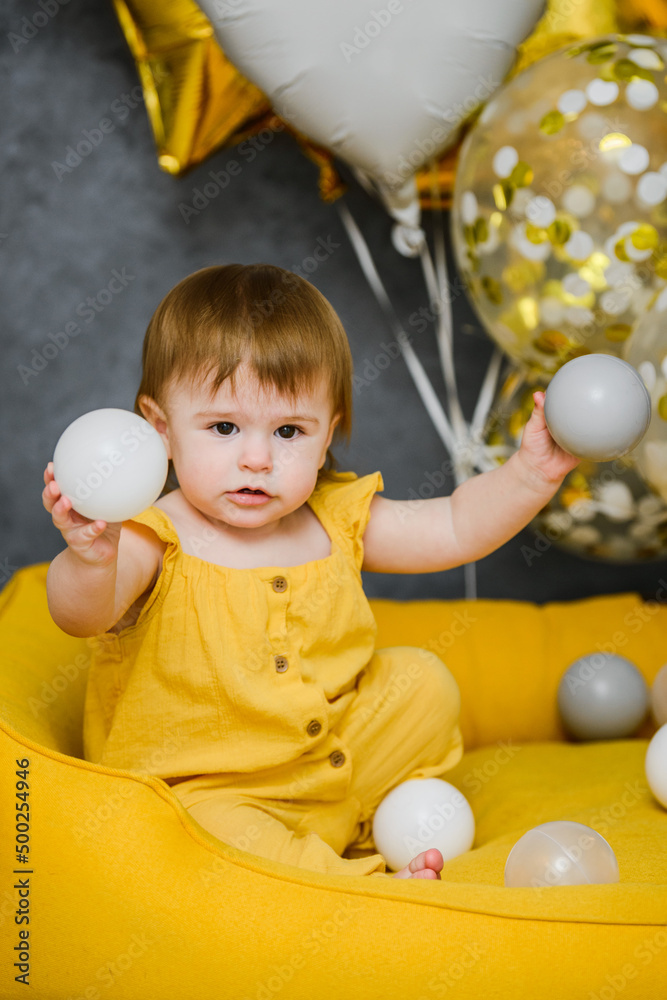Obraz premium 1 year birthday baby playing with ball pool balls