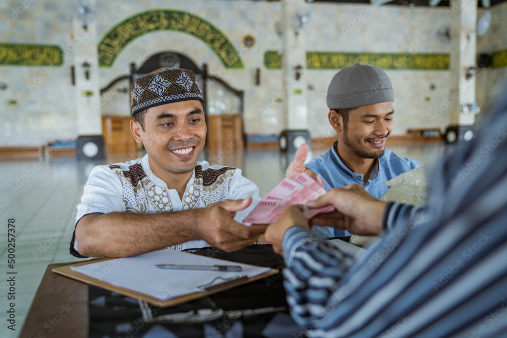 portrait of male muslim paying some zakat charity using cash at the mosque. indonesian money rupiah bank note for zakat portrait of male muslim paying some zakat charity using cash at the mosque. indonesian money rupiah bank note for zakat