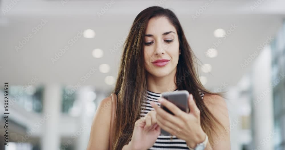 Connected to an online business community. young businesswoman using a smartphone while walking through a modern office.Smiling businesswoman walking and texting on her smartphone Connected to an online business community. young businesswoman using a smartphone while walking through a modern office.Smiling businesswoman walking and texting on her smartphone