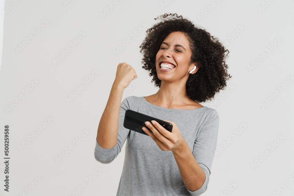 Young hispanic woman gesturing while playing online game on cellphone Young hispanic woman gesturing while playing online game on cellphone